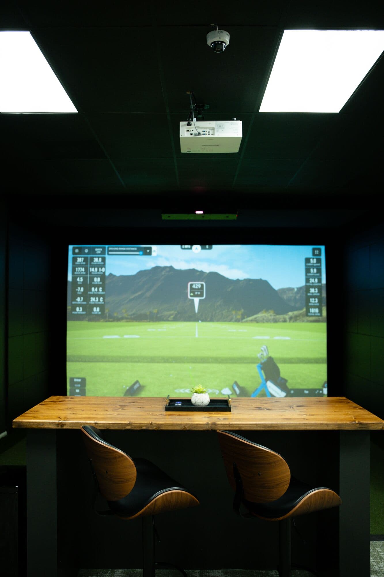 A simulator bay with high-top seating and a mountain course on screen