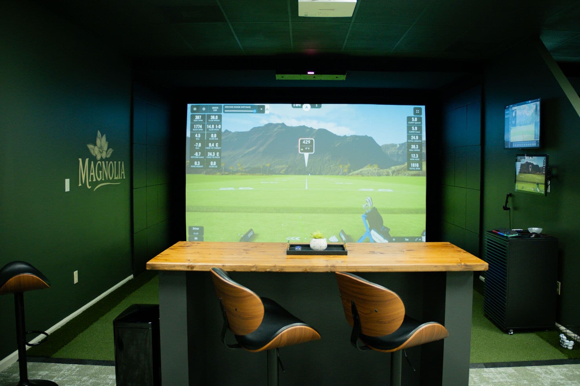 The Magnolia bay with a butcher-block high-top table facing a Uneekor XO2 simulator screen