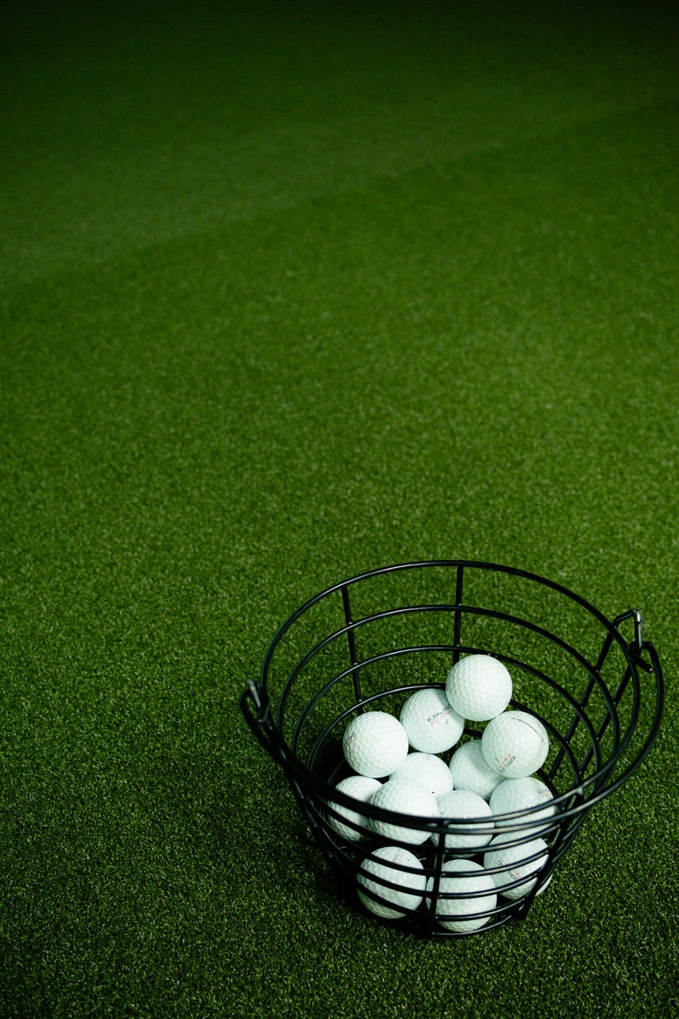 A wire basket of golf balls on the bay turf