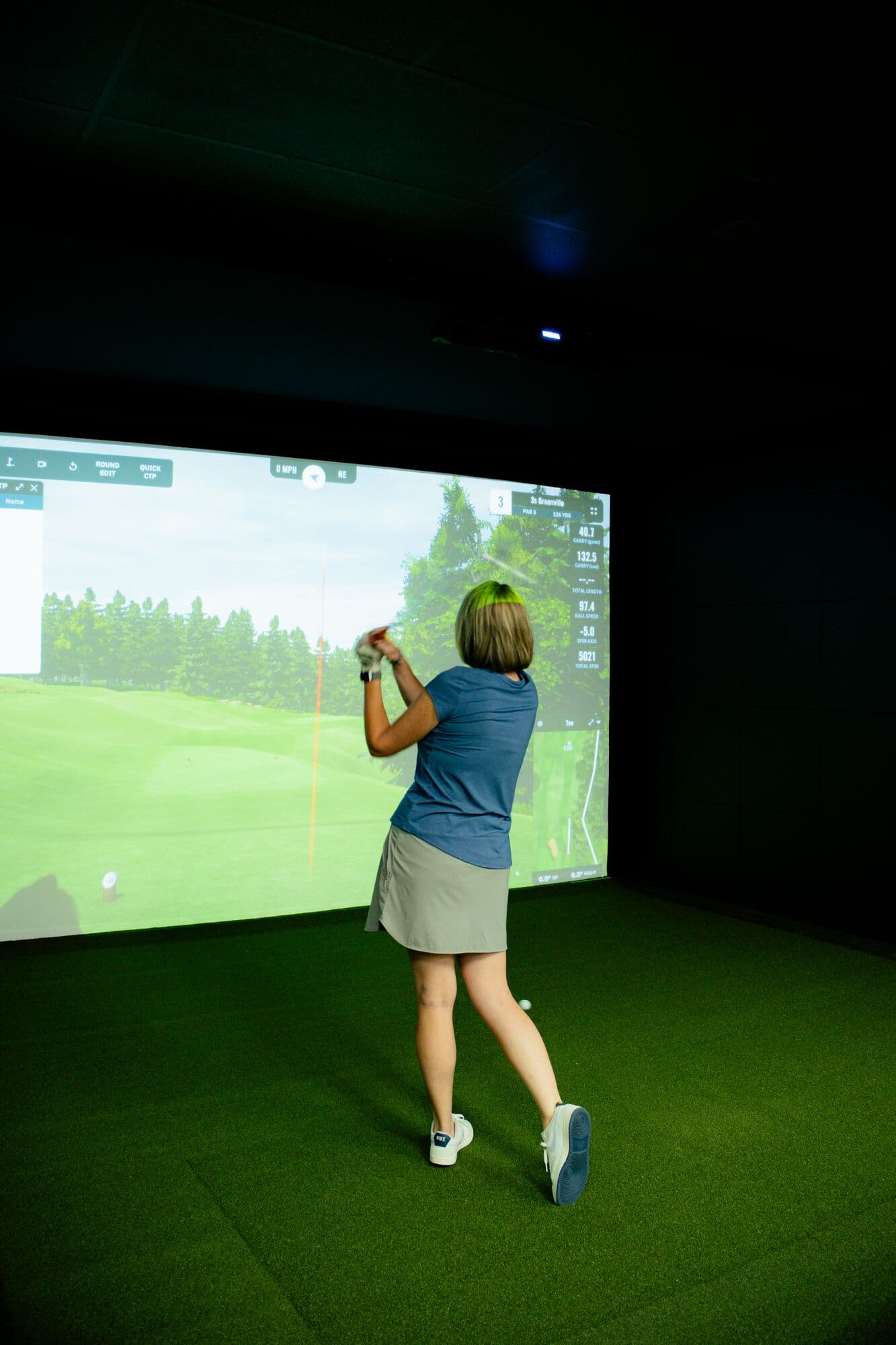 A golfer following through on an iron shot inside a private bay