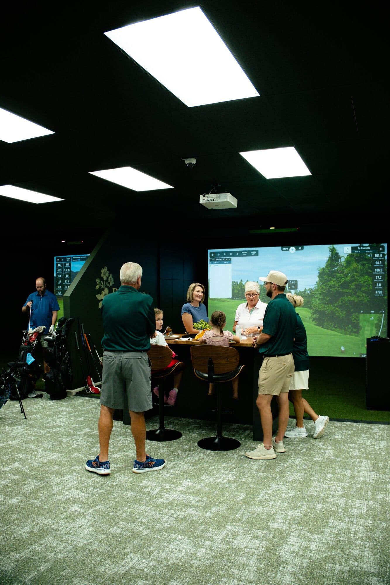 Guests mingling in the clubhouse lounge between simulator bays