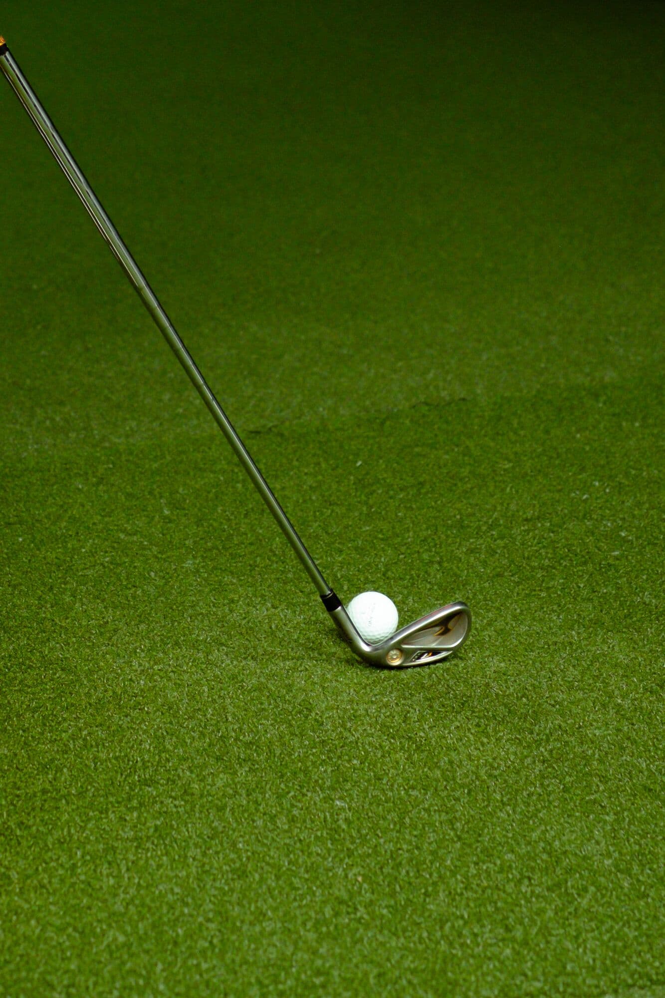 A wedge resting behind a golf ball on the turf